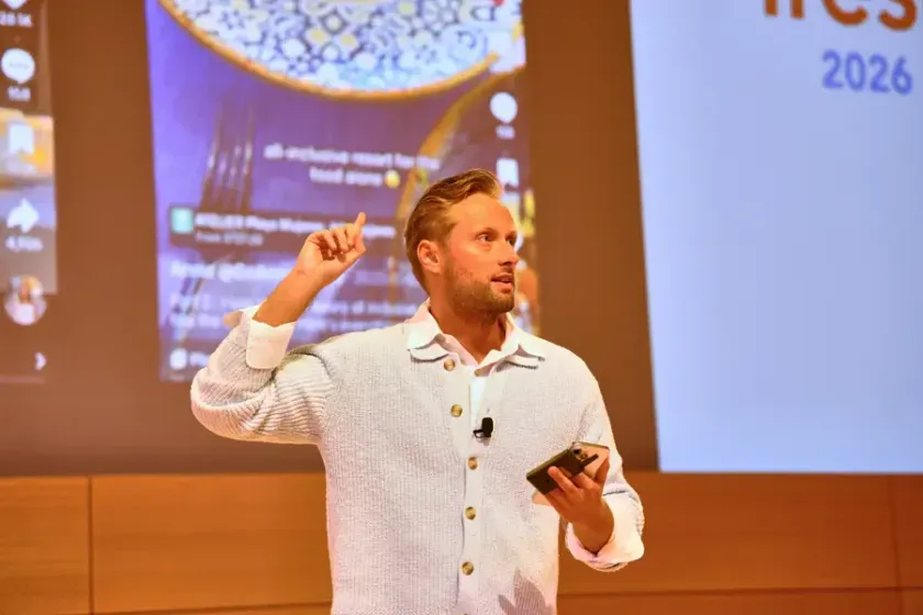 A speaker holding a phone mid-point, 2026
