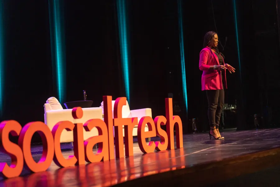 Brandi Rand speaking on stage behind the 3D socialfresh letters, 2022